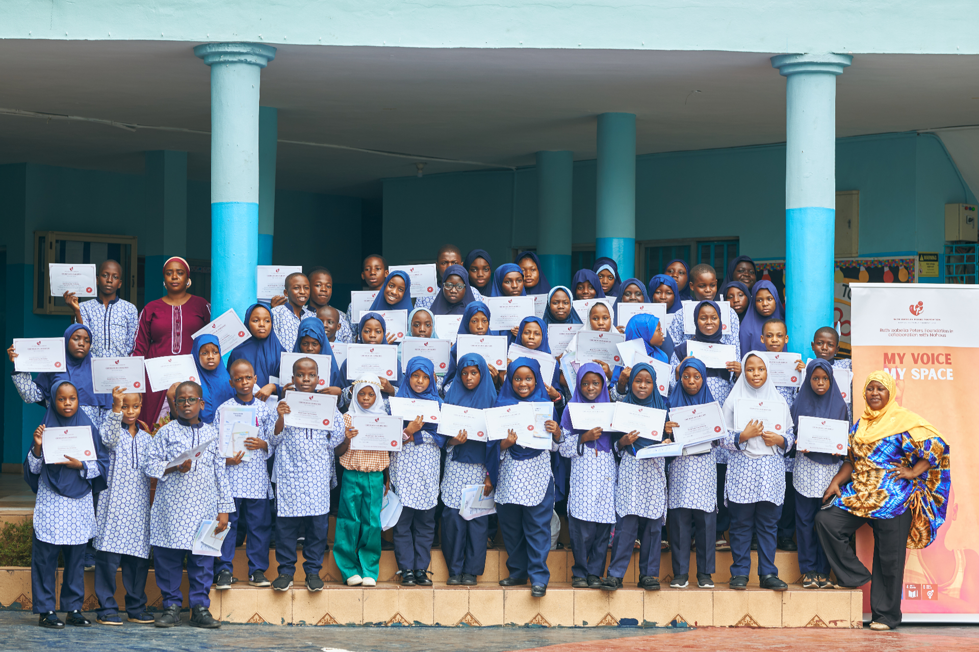 Large group of children holding certificates after a community workshop